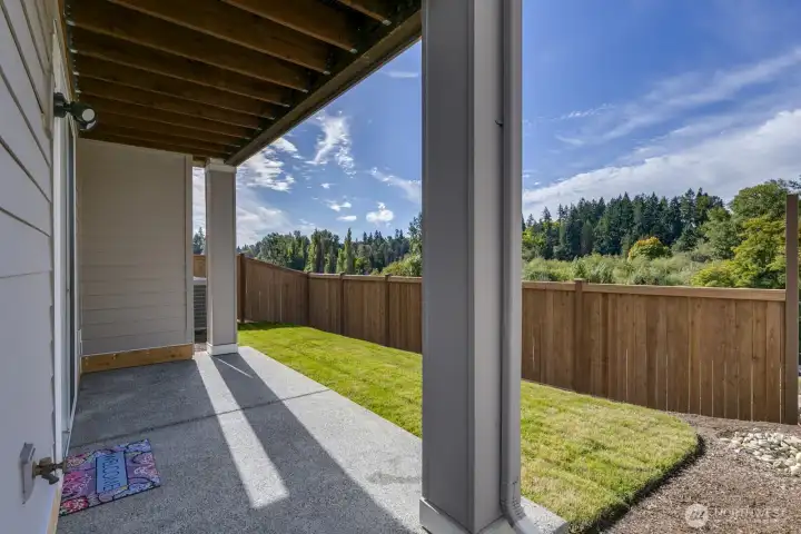 A covered patio offers shade and borders the sunny backyard that is perfect for kids or pets.