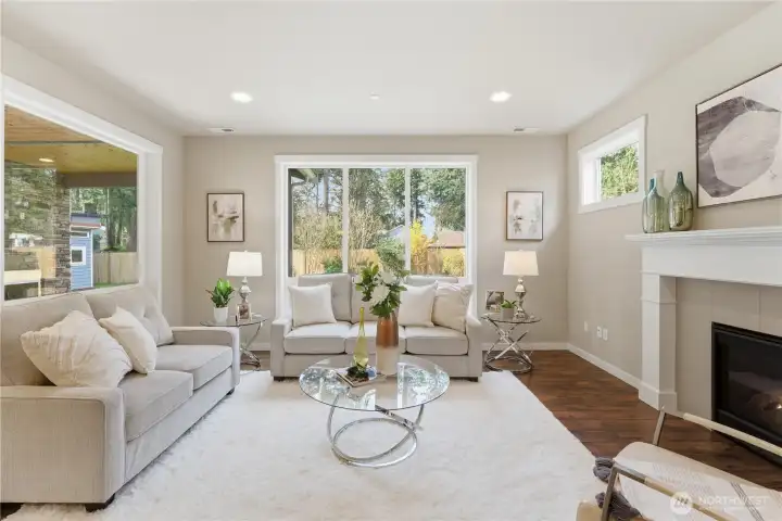 A bright, inviting living room with tall ceilings and a beautiful gas fireplace, filled with natural light