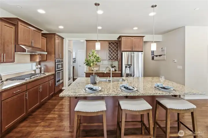 Close-up of the beautiful slab-granite island with pendant lighting, showcasing the full suite of stainless steel appliances