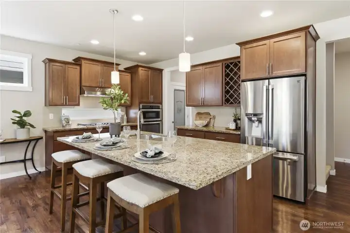 Additional kitchen view showcasing the full suite of stainless-steel appliances and the conveniently placed walk-in pantry in the hallway to the garage