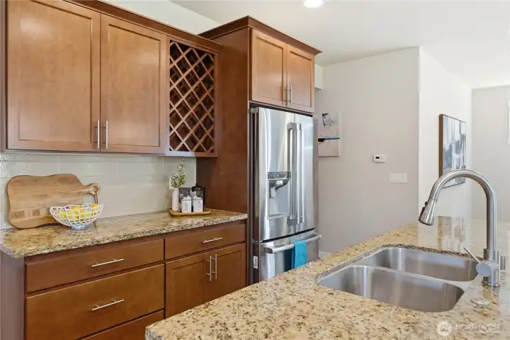Warm cherry cabinetry and a highly functional double sink, complemented by a stainless steel refrigerator with convenient water and ice dispensing