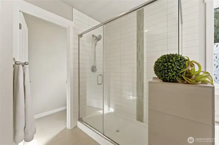 Detail view of the glass-enclosed walk-in shower, with the separate toilet room positioned just ahead for added privacy