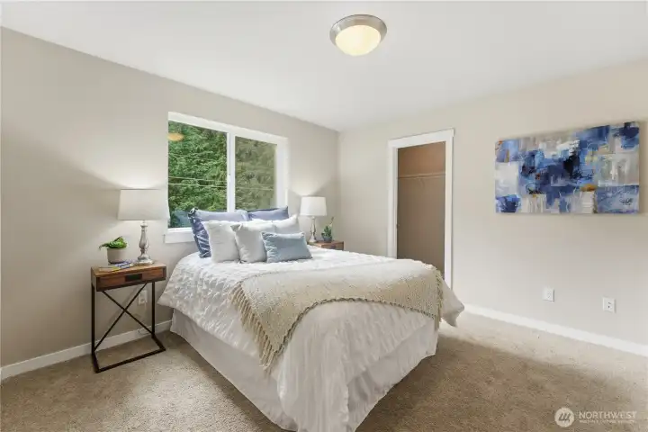 A sunny secondary bedroom with generous light and a spacious closet.   staged with a full bed