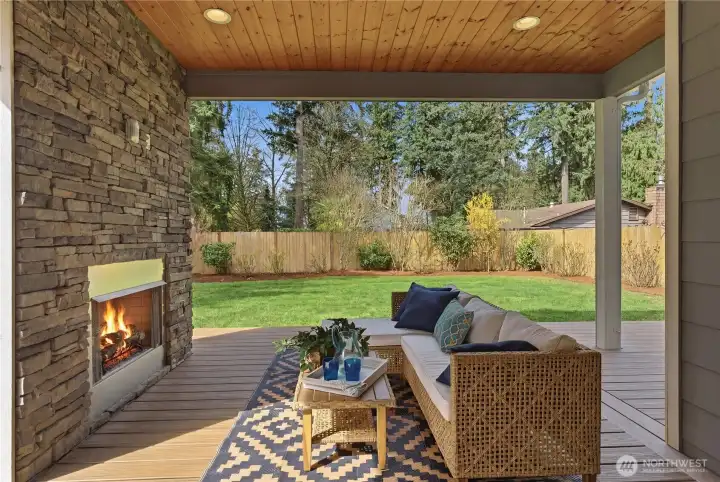 A welcoming covered patio designed for all-season living, complete with a built-in gas fireplace and TV hookup, durable Trex-style decking, and a natural-gas line for effortless grilling