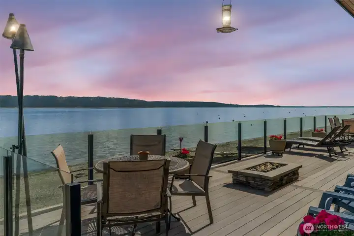 Twilight views set the stage from this expansive no-bank waterfront deck, complete with glass railing, fire feature, and seamless access to the shoreline—perfect for relaxing, entertaining, and enjoying Camano Island’s peaceful coastal setting.