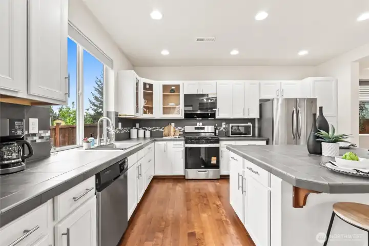 Crisp white cabinetry, stainless steel appliances, designer tile backsplash and expansive windows that flood the space with natural light.