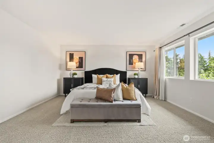 Exceptionally spacious primary suite featuring elegant double-door entry, plush carpeting, and expansive windows that flood the room with beautiful natural light.