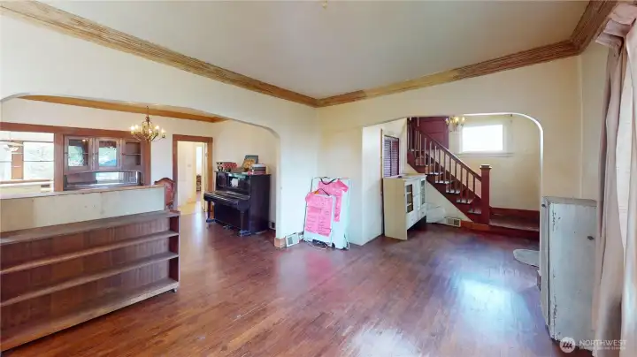 Enter into a semi-formal foyer and one is greeted by stairs to the upper level, a huge living room, coves, arches, and hardwood floors.