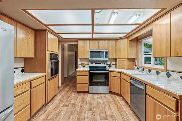 Solid oak kitchen cabinets, vinyl flooring, stainless appliance package (new in 2022) and tile countertops.  Lighting panel is in process of being replaced, please excuse.