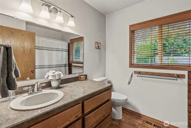 Main floor bath with vinyl floors, oak cabinets, new lighting fixtures and nice window treatments.