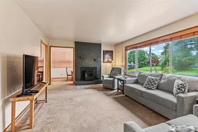 Living room w/pellet insert to keep you warm and cozy; large windows to gaze at the gorgeous landscape and mature surroundings.