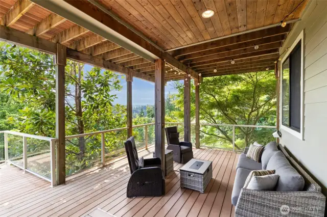 Lovely covered sitting area on the lower level is a perfectly serene spot to surround yourself with nature. Note the elegant wood-clad ceiling.