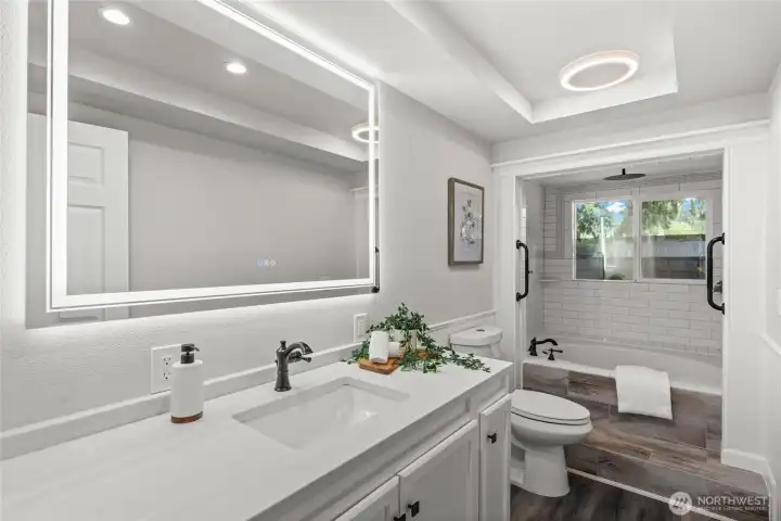 Located in the hall and central to the 3 bedrooms, this conveniently located full bathroom is spacious and beautiful with a large LED vanity mirror, and a new vanity featuring a sleek white quartz counter and abundant storage.