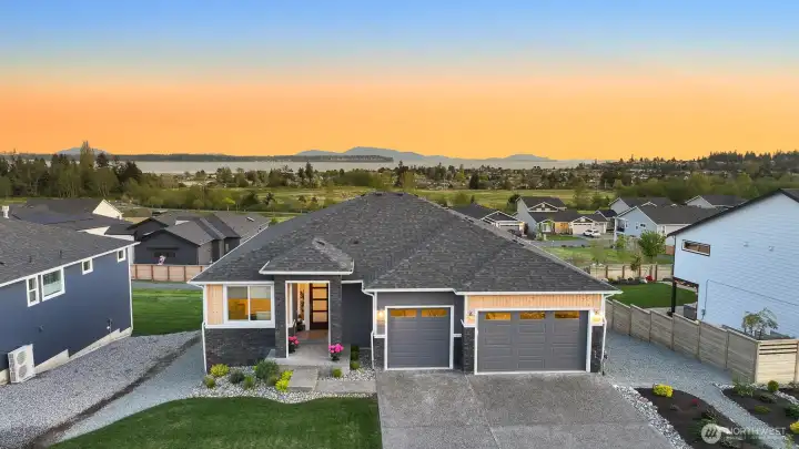 Beautiful front exterior with well-maintained landscaping and welcome entry set against a stunning sunset backdrop.