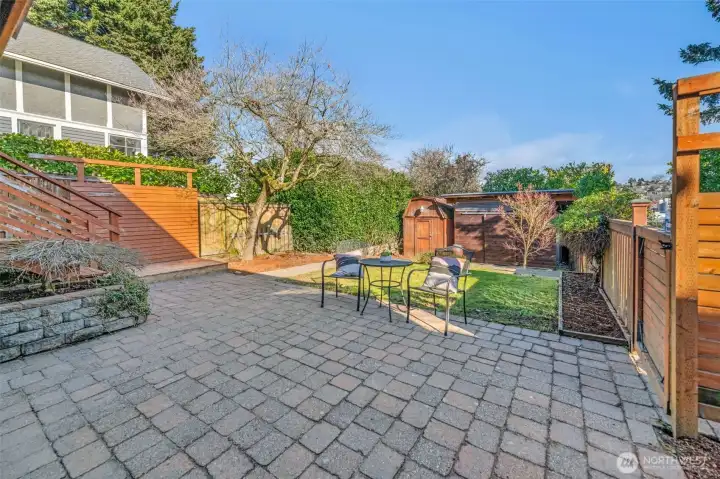 Patio area and terraced backyard with 2 outbuildings