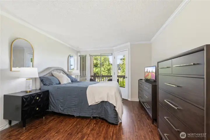 The primary bedroom offers direct deck access and peaceful views of the surrounding greenery.