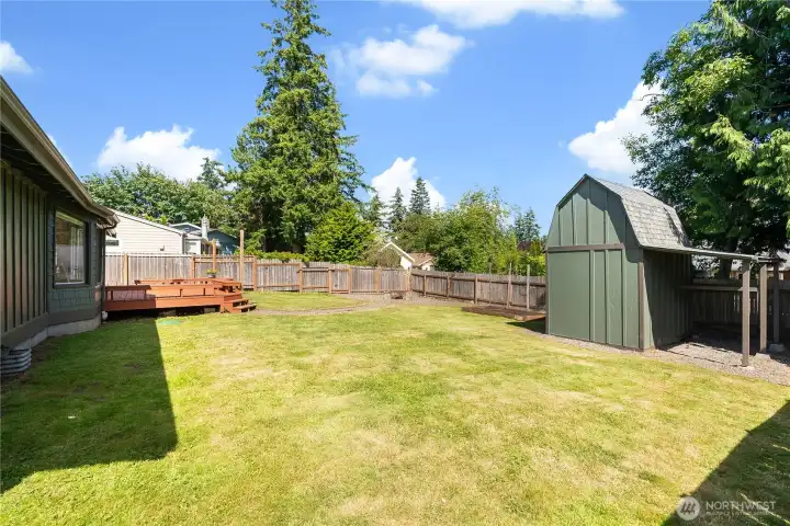 Fully fenced backyard with a storage shed, graveled fire pit, and raised garden bed. Fully fenced backyard with a storage shed, graveled fire pit, and raised garden bed.