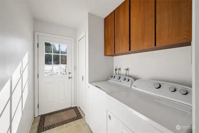 Utility room with storage cupboards leads to the solid back deck.  All appliances stay.