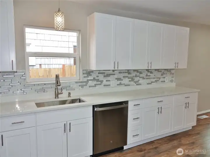 Stylish tile backsplash with quartz counters and beautiful white cabinets.