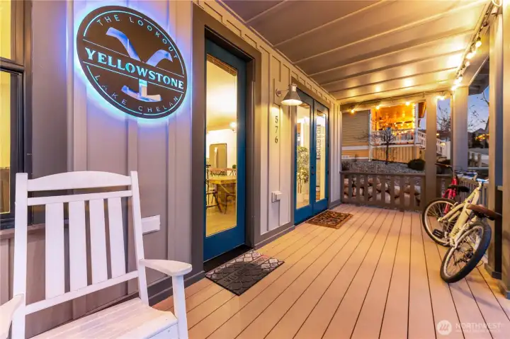 Twilight view of classic covered front porch with French doors and custom lighted sign.