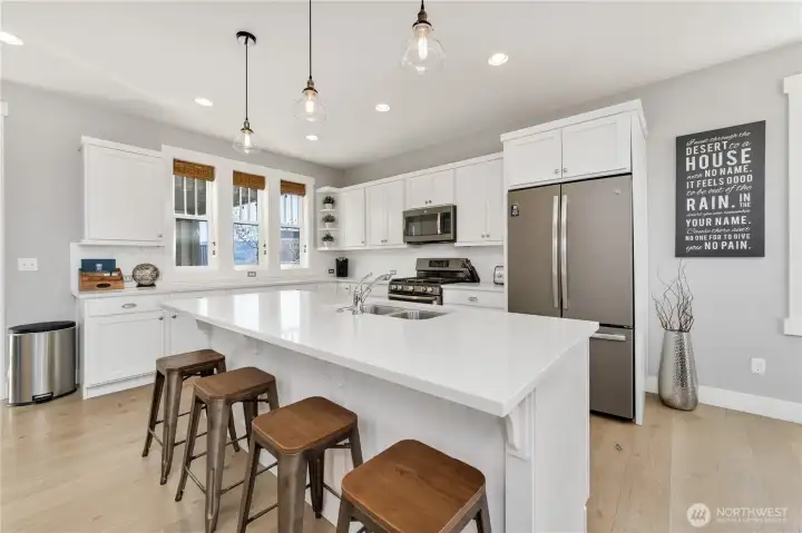 Kitchen with quartz countertops, stainless steel appliances and a sit up bar.