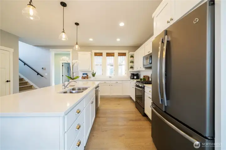 Kitchen with large island, quartz countertops and stainless steel appliances.