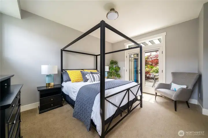Main level Primary bedroom with en-suite bath and French doors leading to the sunny outdoor living area.