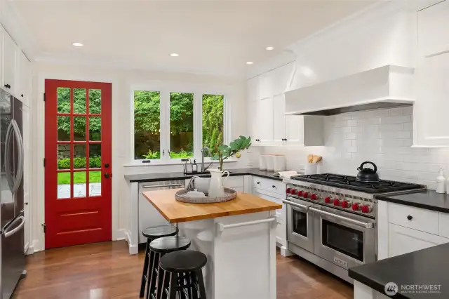 Kitchen with honed granite counters, subway tile and a wolf range.  the red door leads to the backyard and the patio.