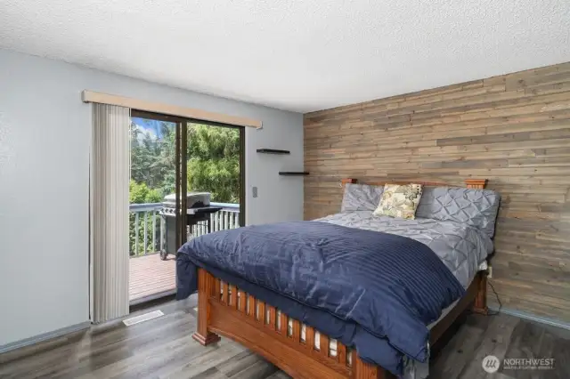 Dramatic wood wall enhances the primary bedroom wall with slider to full length deck overlooking golf course and back yard