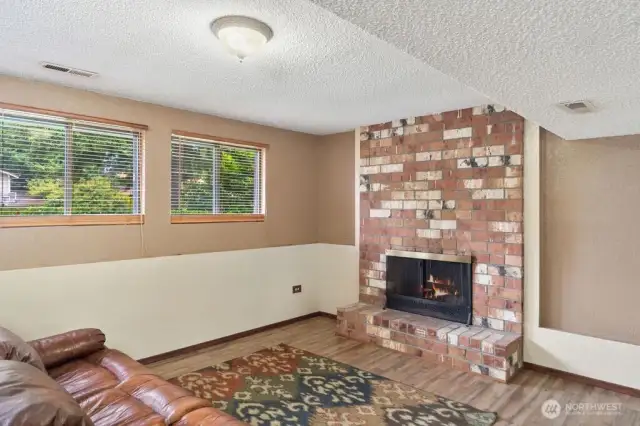 Very spacious rec room with brick fireplace & access to the covered downstairs patio .