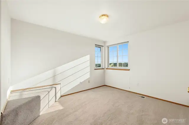 Corner bedroom with sitting area and partial views from each window.