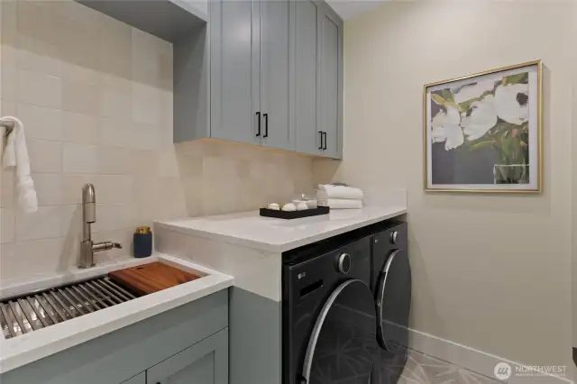 Spacious separate laundry room with ample built in storage, countertop space, and a deep utility sink.