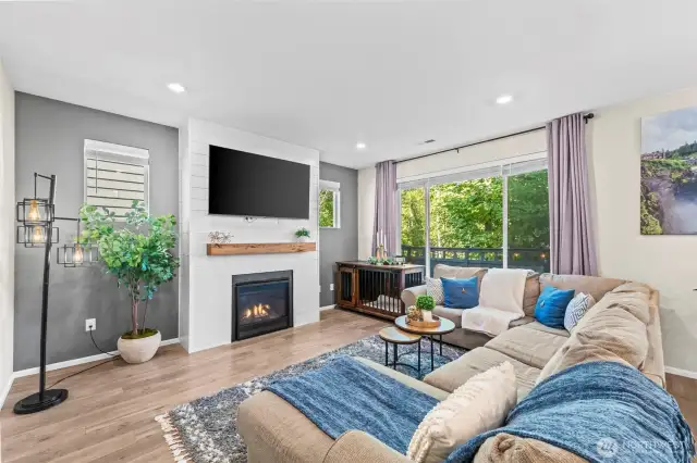 Cozy living room with fireplace, large windows, and backyard views – ideal for relaxation.