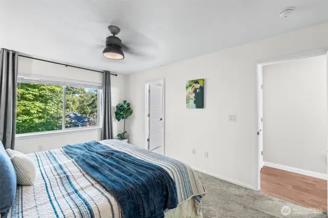 Primary bedroom with abundant natural light, plush carpet, and room for king-size furniture.