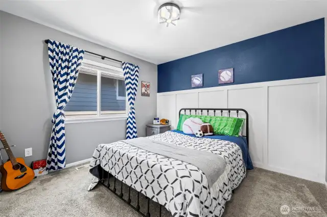 Bedroom with stylish accent wall and plenty of natural light.
