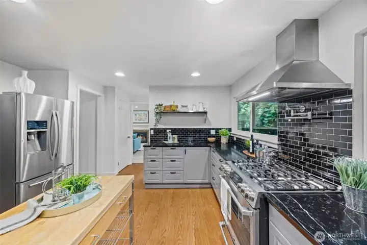 With room for an island, and stunning high-end appliances, this is a chef's paradise.. There's even an integrated pot filler over the giant 6-burner stove and custom backsplash!