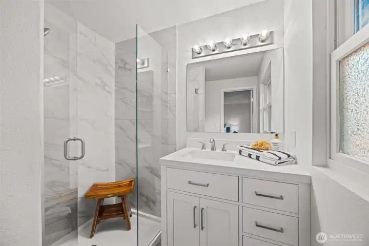 This primary bathroom has no expense spared! High end tilework, custom glass shower doors, a brand new vanity and lighting!
