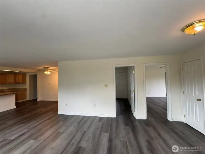 Living room looking at (from left to right) kitchen/dining area, bedroom 2, primary bedroom, & main entrance.