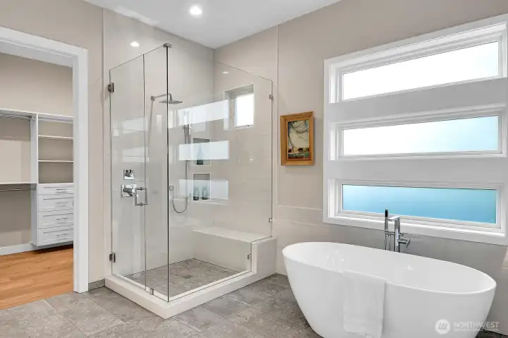 Main level primary ensuite complete with soaking tub, heated tile floors, floor to ceiling tiled shower w/ bench, floor motion sensor lights, custom walk-in closet, double quartz vanities, private toilet room...