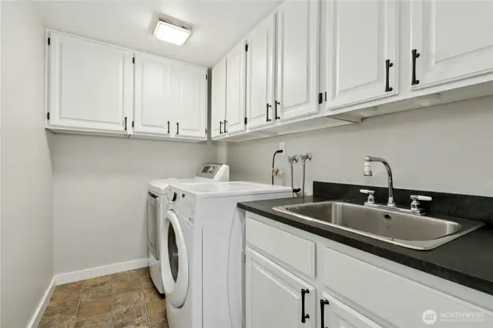 A great laundry room with lot's of cabinets, a sink and the washer & dryer stay for you.