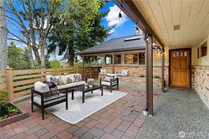 Covered walkway leads to front entry with classic mid-century appeal. Welcoming paver patio for dining alfresco surrounded by flowers and twinkling garden lights.