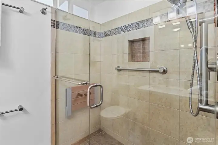Large shower with frameless glass shower enclosure and shampoo niche.