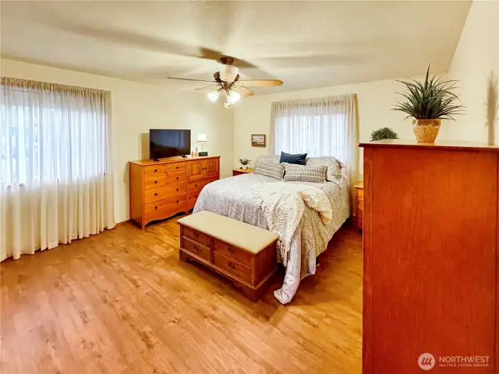 Big primary features laminate flooring and ceiling fan.