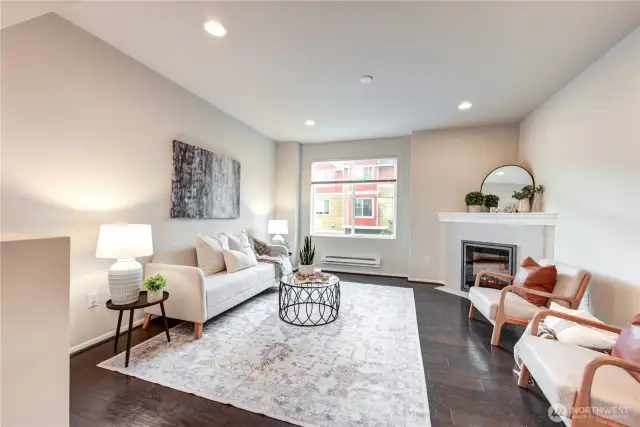 Living room with tall ceilings, engineered hardwood flooring & a fireplace.