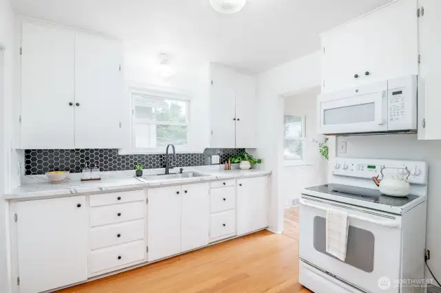 This refreshed kitchen has new a countertop, tiled backsplash, sink, faucet, and hardware.