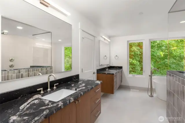 Expansive primary bath features duel custom floating vanities, free standing soaking tub, heated tile floors and frameless glass enclosed shower with duel heads