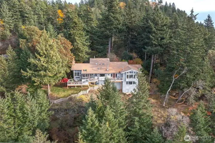 Aerial view of the west face of the home nestled in native vegetation.