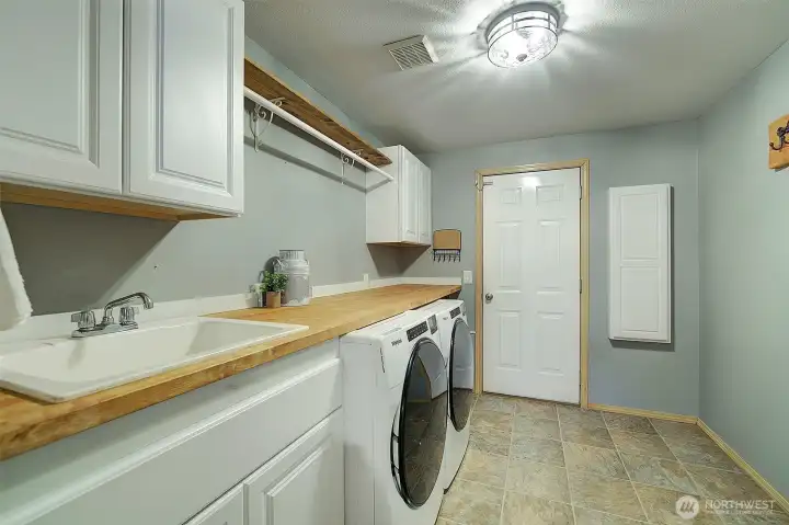 Super functional laundry room, with cabinets, sink, folding counter, hanging rack and in the wall ironing board.