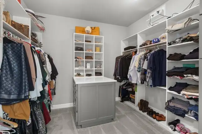 Luxurious primary closet with built-ins, island with quartz counter.