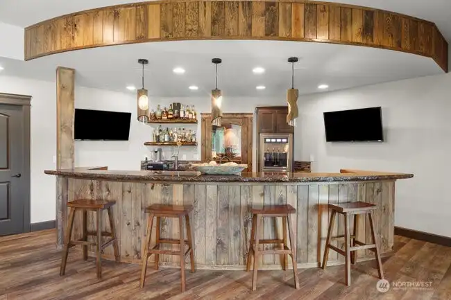 Expansive bar reminiscent of a wine barrel equipped with amenities that would be a bartenders dream including an 894 bottle wine cellar, beverage fridge, kegerator with beer taps, wine dispenser machine, commercial ice maker.